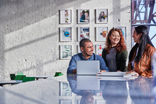 Three people working around a laptop